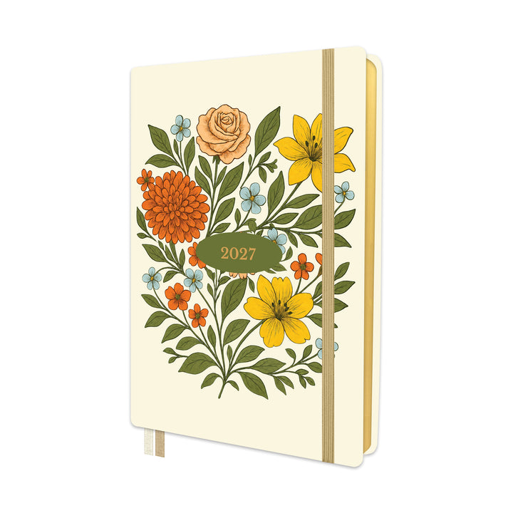 A cream-colored 2027 pocket calendar or planner with a retro floral illustration on the cover, featuring yellow, orange, and blue flowers with green leaves, held closed by a beige elastic band. 