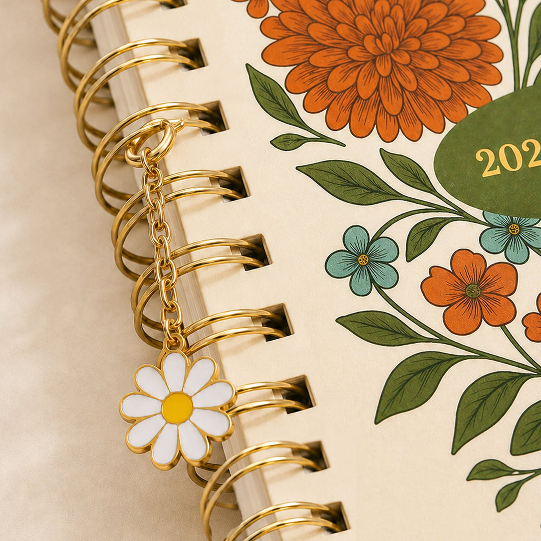 Planner with floral design and gold spiral binding featuring a daisy charm. 