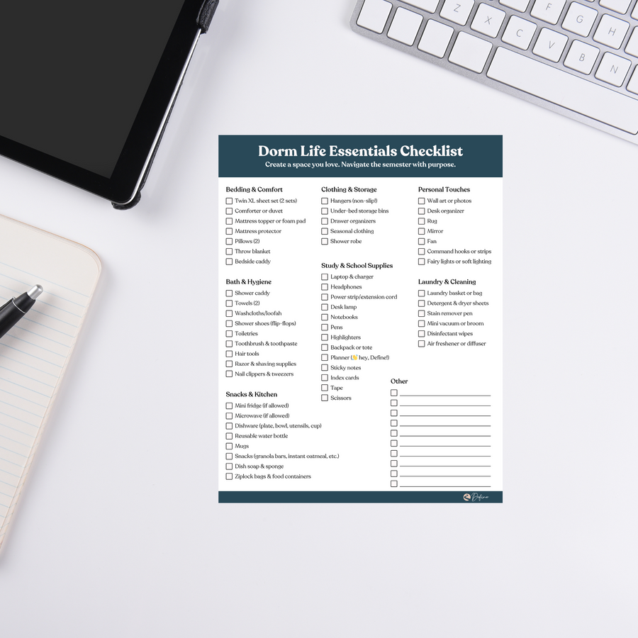 Dorm Life Essentials Checklist notepad on white desk with keyboard, tablet, and pen. Ideal for students organizing school supplies and dorm needs.