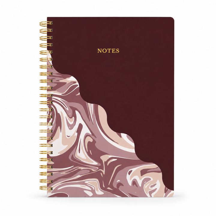 Notebook with marbled design and gold spiral binding on a white background 