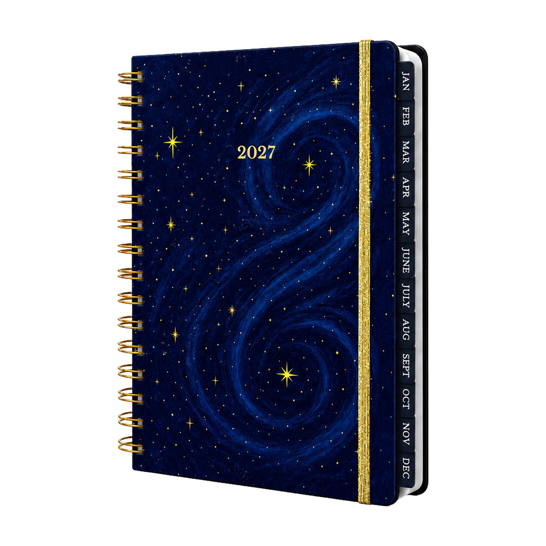 A 2027 spiral-bound planner with a deep blue galaxy night-sky cover, featuring gold stars and a gold glitter spine band with monthly tabs labeled JAN through NOV. 