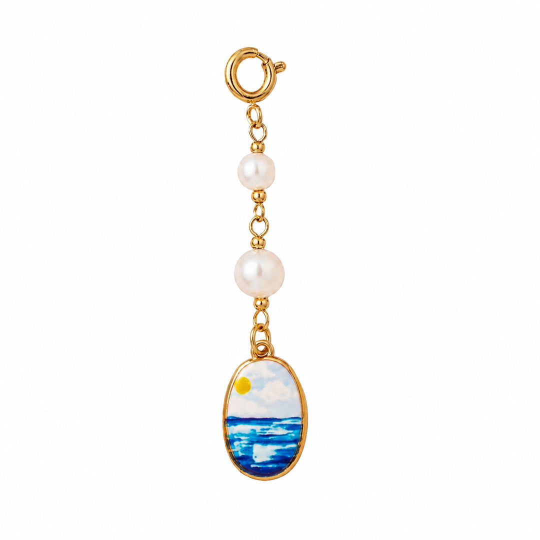 Gold charm with pearl and ocean scene on a white background 