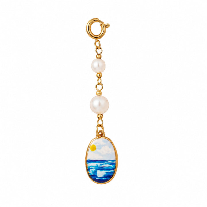 Gold charm with pearl and ocean scene on a white background 