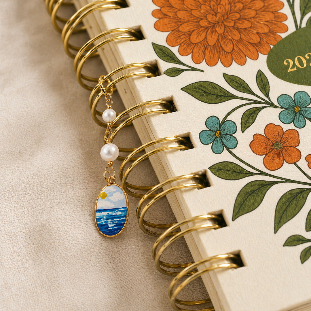 Decorative keychain with a scenic pendant on a floral planner 