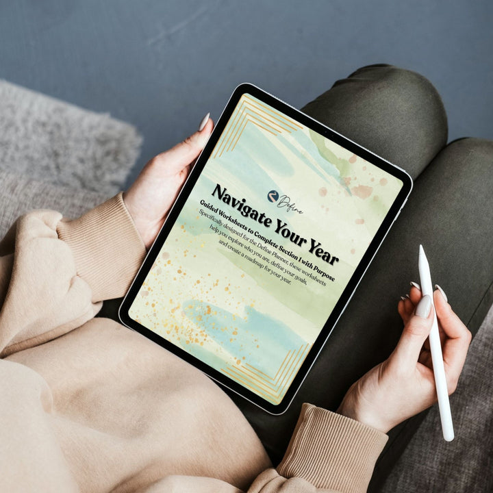 Person holding a tablet with a digital product that says Navigate Your Year on the screen, sitting on a couch.