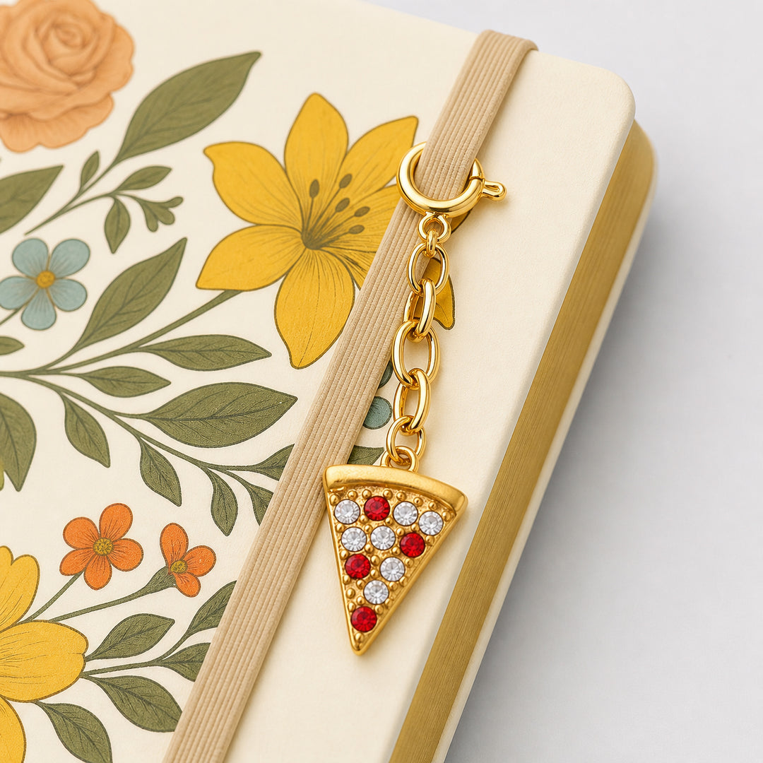 Gold pizza slice charm on a beige strap against a floral planner cover 