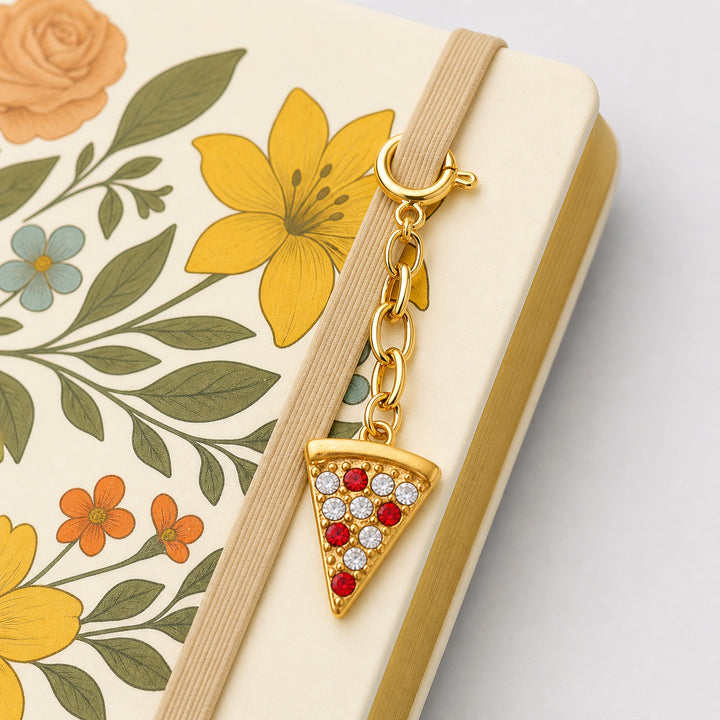 Gold pizza slice charm on a beige strap against a floral planner cover 