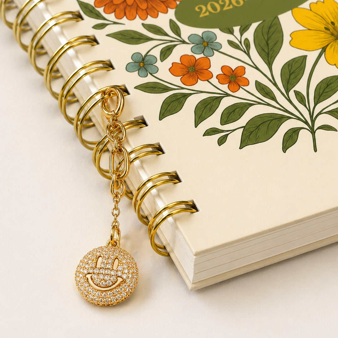 smiley face gemstone charm attached to the gold spiral on the planner 