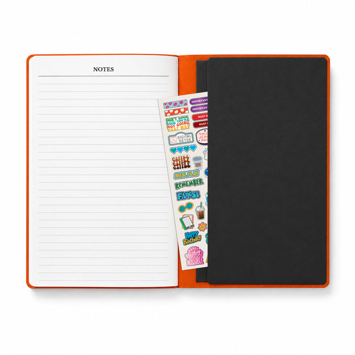 Open notebook with lined pages and a sticker sheet on an orange cover 