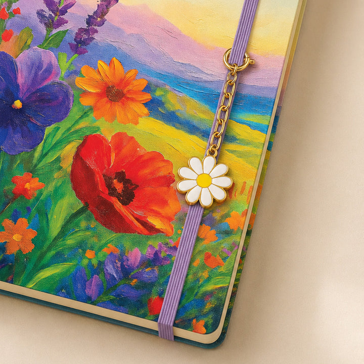 Notebook with a floral design and a purple ribbon bookmark featuring a white flower charm. 