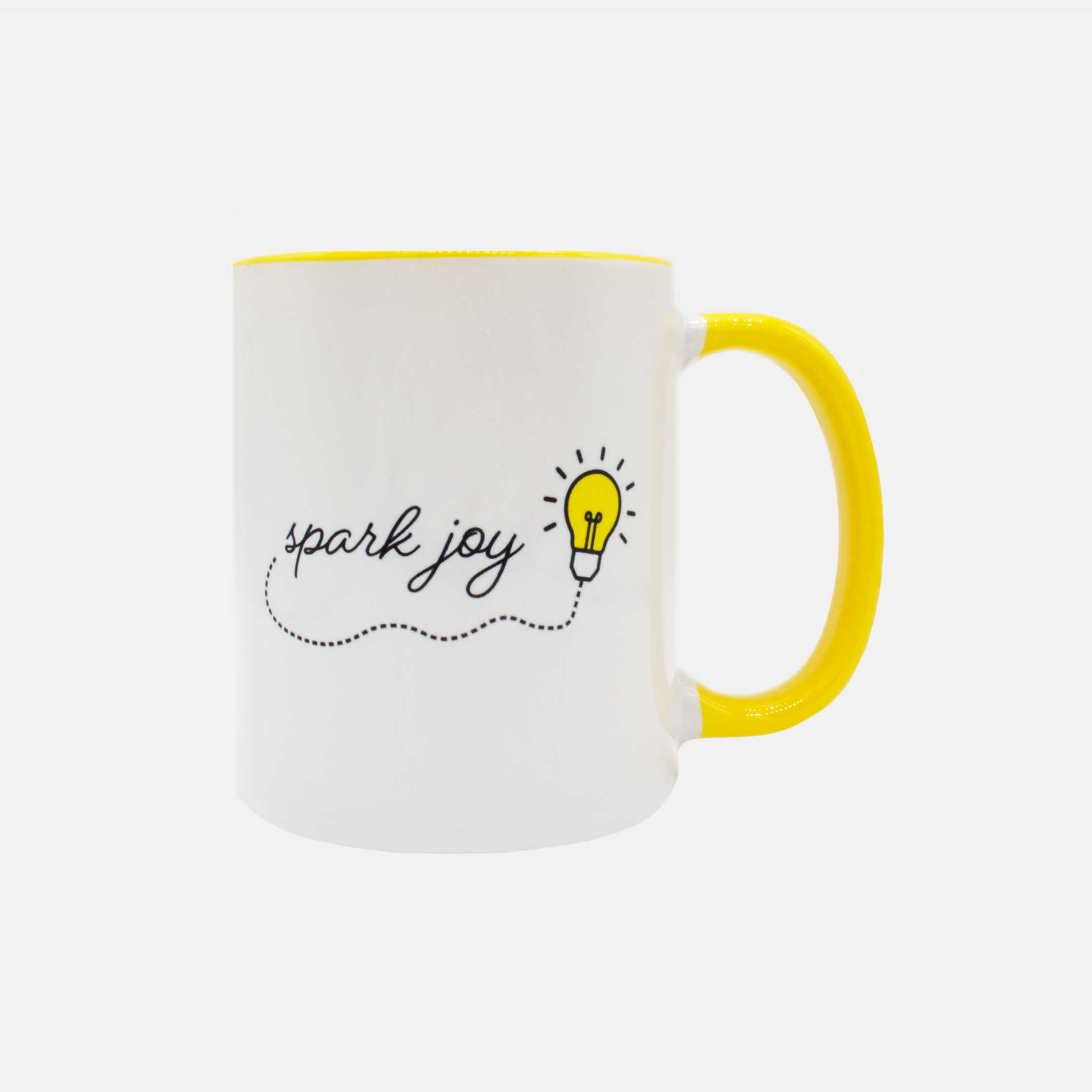 Front of the white mug with yellow handle and the words spark joy and a lightbulb on the front. #color_yellow